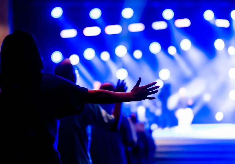 Vibrant concert scene with people raising hands, capturing the energy and spirituality of the moment.
